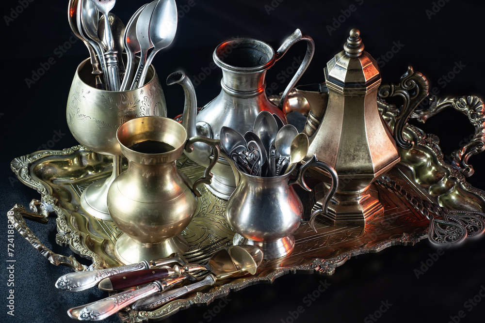 Antique silver cutlery on a dark background in a composition on a table. Antique silver cutlery on a dark background in a composition on a table.