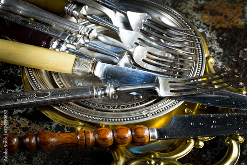 Antique silver cutlery on a dark background in a composition on a table.