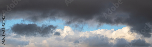 A heavy dark cloud hangs over a white cloud in a blue sky