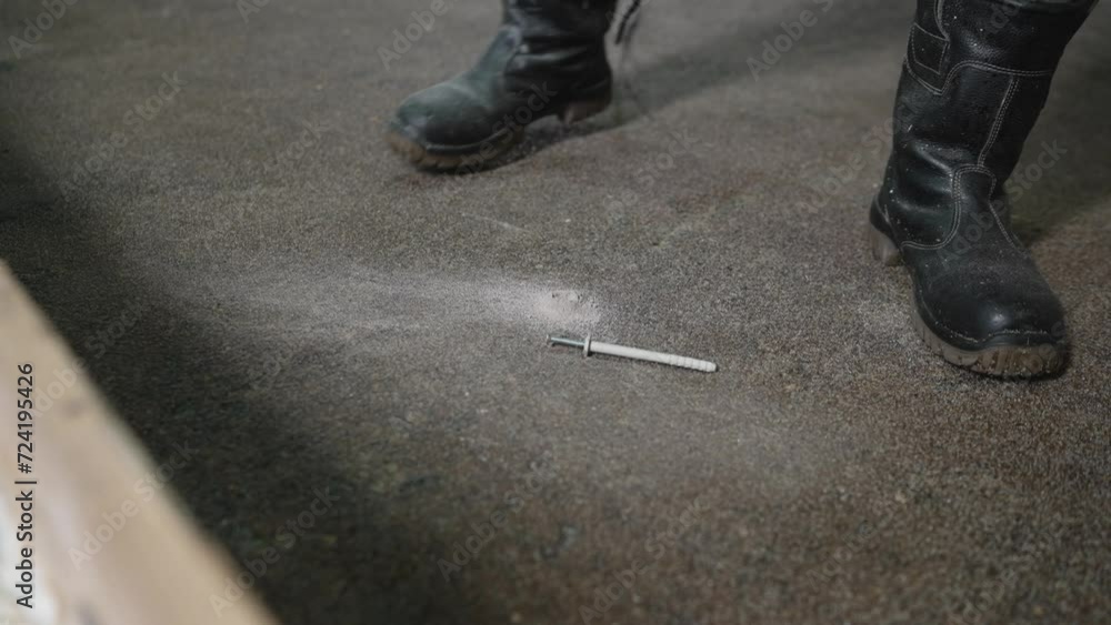 Drilling and installing dowels in the floor. One man drills a hole in the floor with a hammer drill to laser level the floor. Drilling and installing dowels in the floor. One man drills a hole in the floor with a hammer drill to laser level the floor.