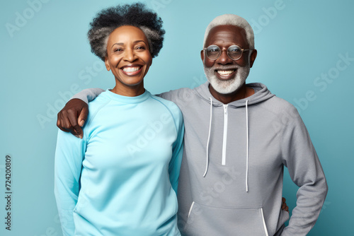 Portrait of Elderly afro-american smiling couple posing over blue background. Mature adults wear activewear sportswear. Sport clothes for retired people man and woman. Coy space for text and design.