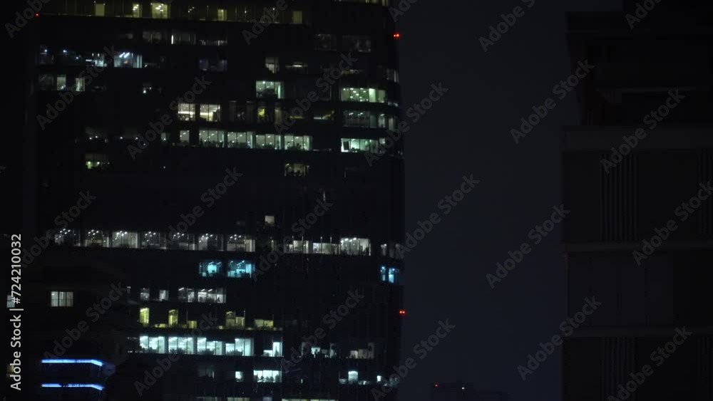 Night skyscraper with office windows, business people working at night. Office windows in a glass skyscraper Night skyscraper with office windows, business people working at night. Office windows in a glass skyscraper