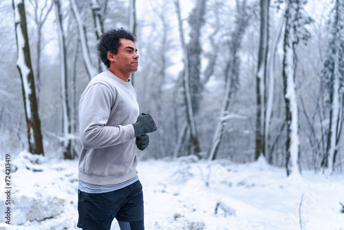 Man jogging in winter, surrounded by nature covered in snow. © DusanJelicic