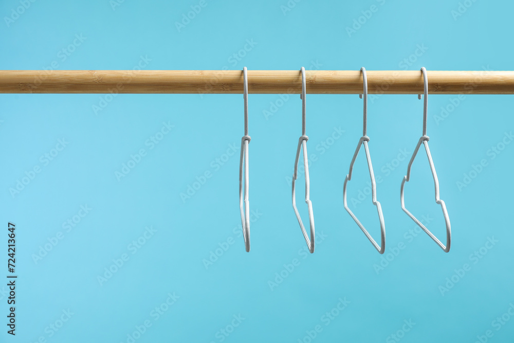 Empty clothes hangers on wooden rack against light blue background. Space for text Empty clothes hangers on wooden rack against light blue background. Space for text