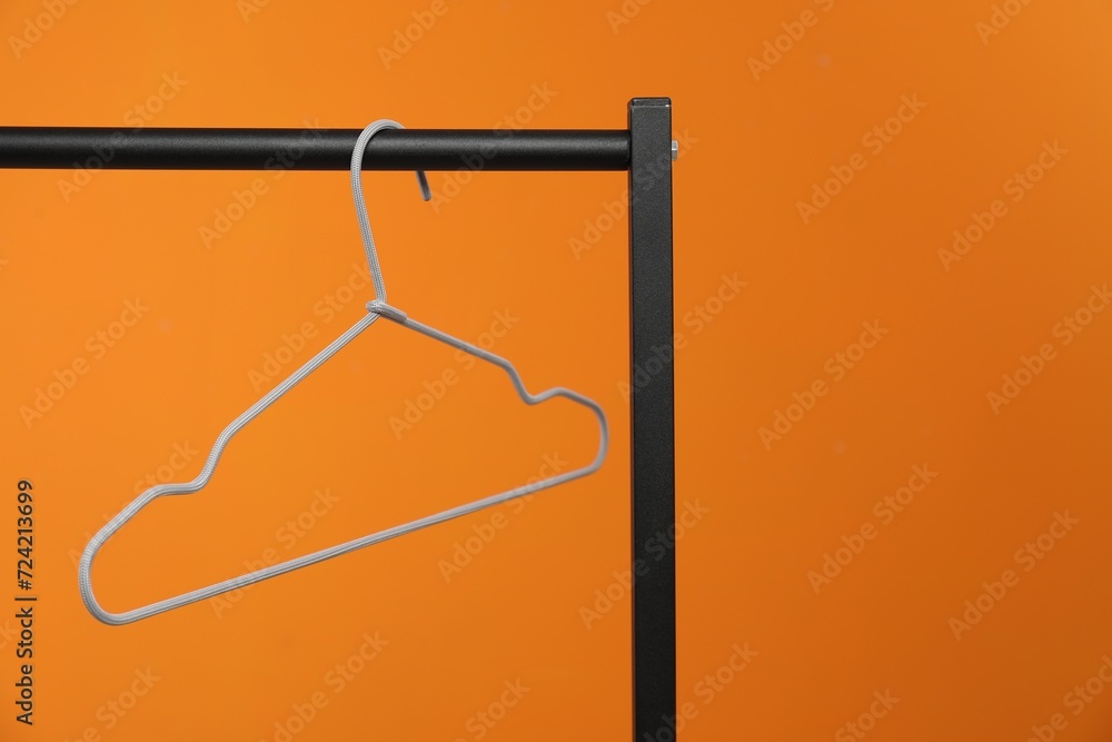 Empty clothes hanger on rack against orange background. Space for text Empty clothes hanger on rack against orange background. Space for text