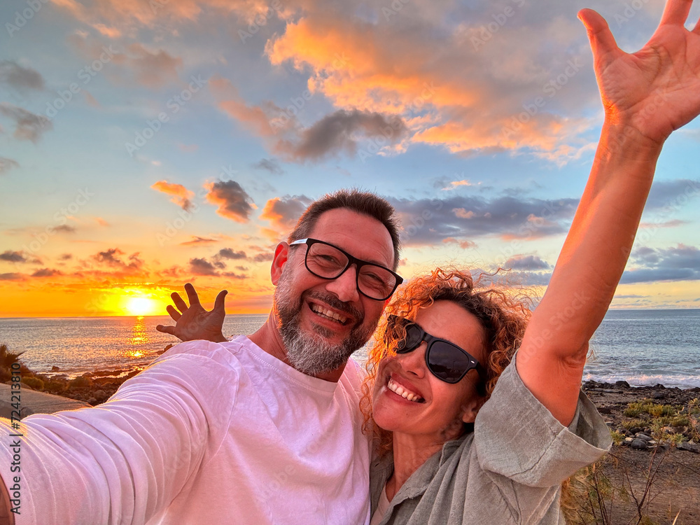 Happy adult traveler enjoy sunset in tropical destination beach together having fun and taking selfie picture to share on social media. Traveler influencer lifestyle. People summer holiday vacation - obrazy, fototapety, plakaty 