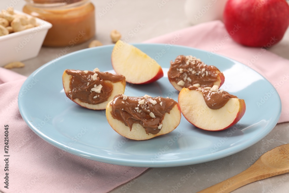 Slices of fresh apple with nut butter and chopped nuts on table, closeup