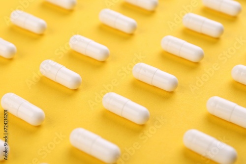 Many vitamin capsules on orange background, closeup
