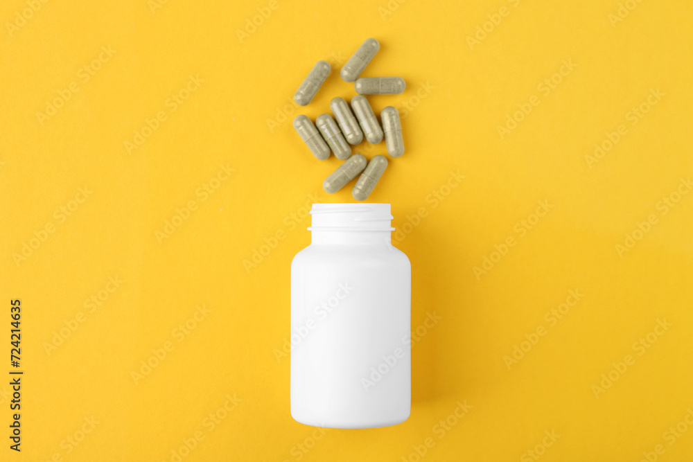Bottle and vitamin capsules on yellow background, top view Bottle and vitamin capsules on yellow background, top view