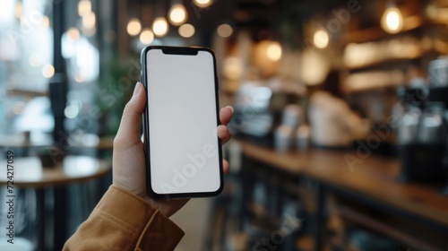 A Woman's Hand Holding a Phone with White Blank Screen at a Coffee Shop
