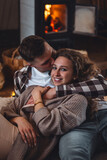 Concept of happy family relationships between man and woman. Young couple relaxed near fireplace in a cottage countryside house. Cozy atmosphere, calm lazy weekend, slow living , simple pleasures