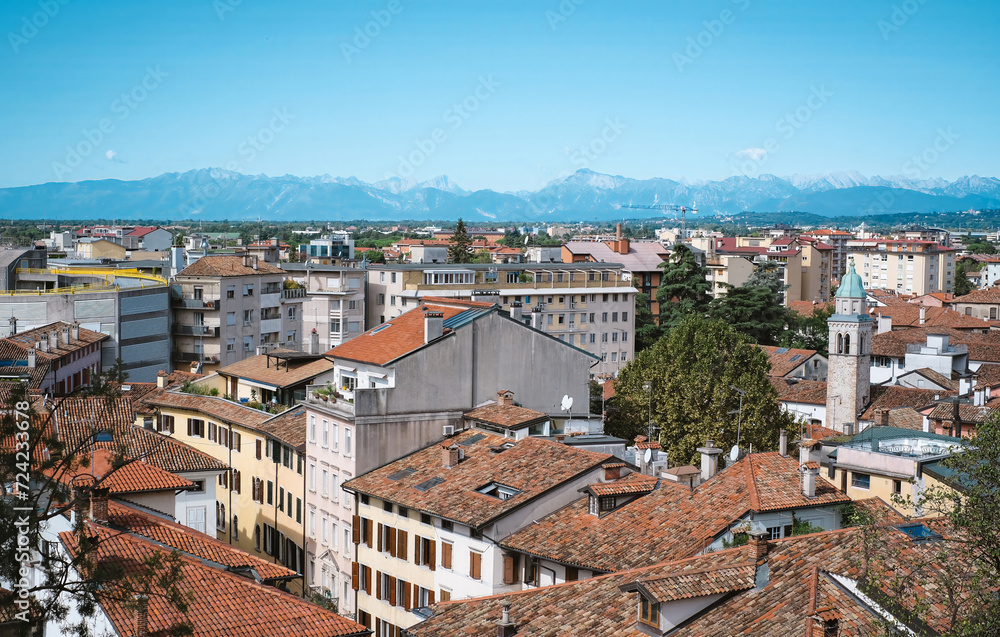 A panoramic view on Udine, Italian city with many buildings and mountains on the background