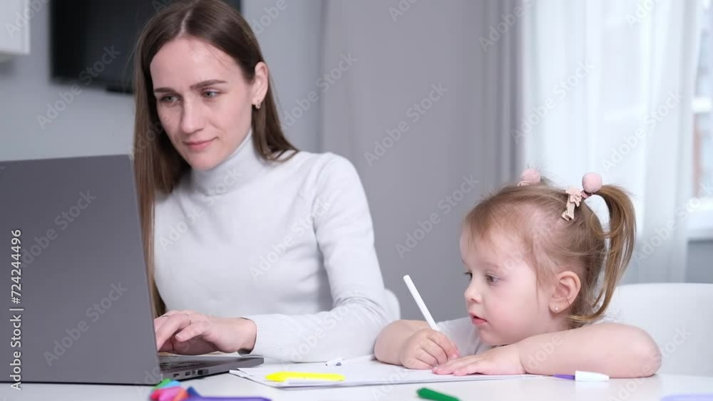 caucasian Mother multi-tasking with preschooler daughter using computer laptop at home. Candid authentic and real life mom working and parenting kid. caucasian Mother multi-tasking with preschooler daughter using computer laptop at home. Candid authentic and real life mom working and parenting kid.