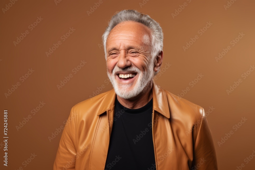 excited senior man in leather jacket looking at camera on brown background