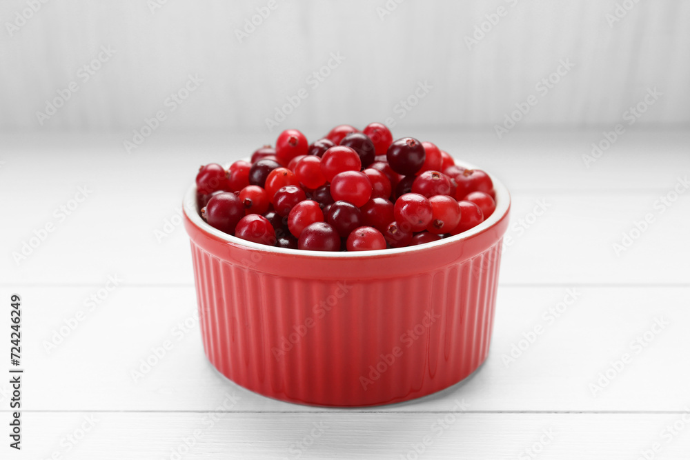 Fresh ripe cranberries in bowl on white wooden table, closeup Fresh ripe cranberries in bowl on white wooden table, closeup