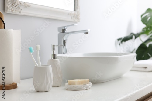 Different bath accessories and personal care products near sink on bathroom vanity