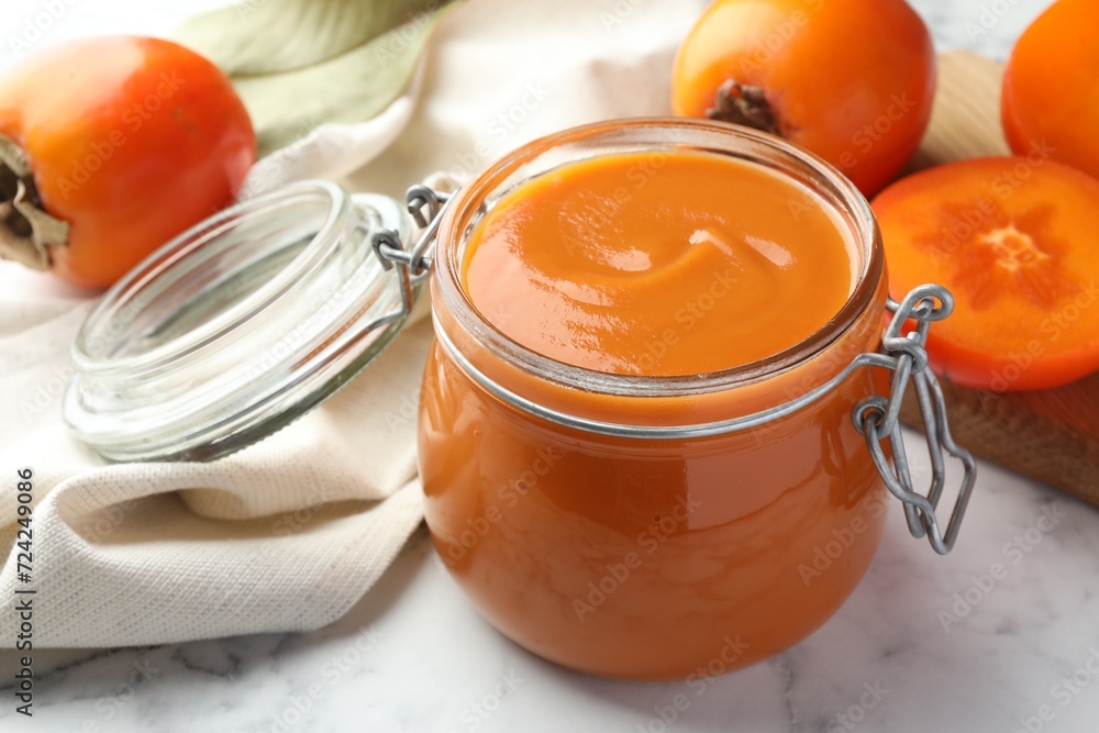 Delicious persimmon jam and fresh fruits on white marble table, closeup Delicious persimmon jam and fresh fruits on white marble table, closeup