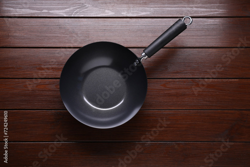 Empty iron wok on dark wooden table, top view. Chinese cookware