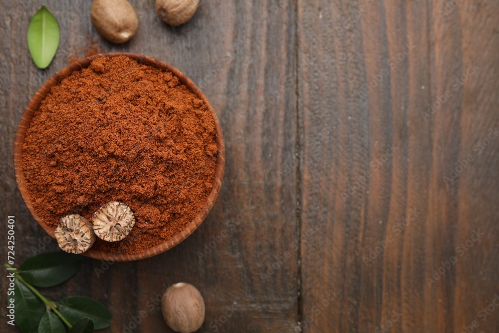Nutmeg powder in bowl, seeds and green leaves on wooden table, flat lay. Space for text Nutmeg powder in bowl, seeds and green leaves on wooden table, flat lay. Space for text