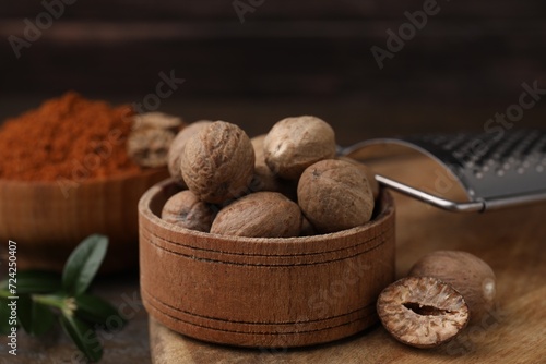 Nutmegs in wooden bowl and grater on table