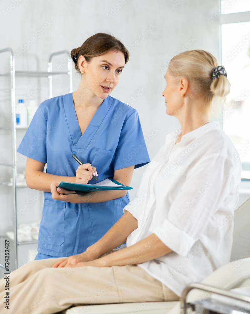 Fototapeta premium Physician listening to her patient during consultation while patient on couch in office of modern medical center.