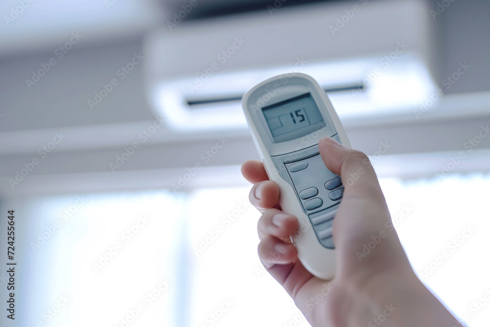 Close up image of hand holding an air conditioning remote control and adjusting the temperature Close up image of hand holding an air conditioning remote control and adjusting the temperature