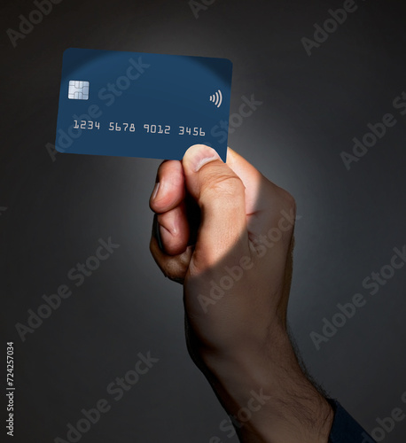 A credit card in a man’s hand is spotlighted in this 3-d illustration. Blank space on the card is avaliable for use for text or graphic information. photo