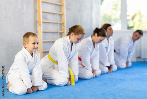 Family in gym at group karate training with trainer are in sitting position