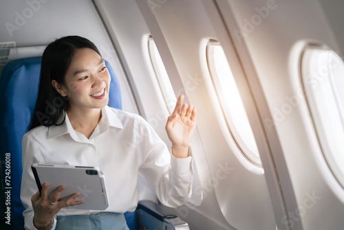 Female asian woman holding Tablet while sitting in airplane.