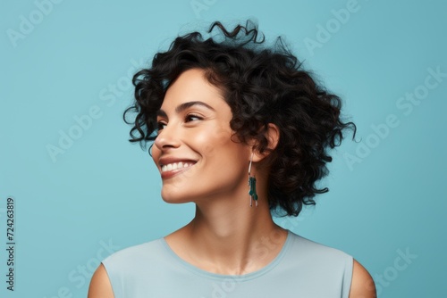 Portrait of beautiful young woman with curly hair on blue background.