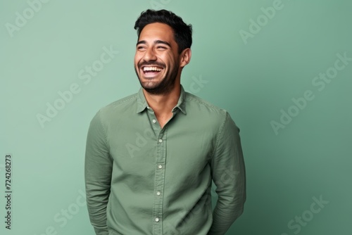 Portrait of a happy young asian man laughing on green background