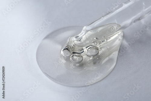 Pipette with cosmetic serum on white background, macro view