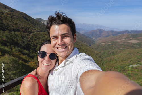 Young latin couple taking selfie at mountain peak. Tourism, nature and active lifestyle concepts.