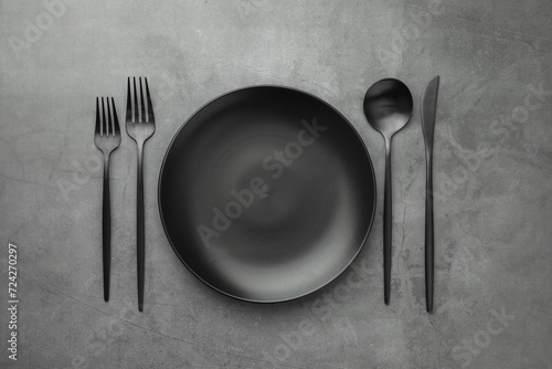 Empty plate and cutlery on grey table, flat lay