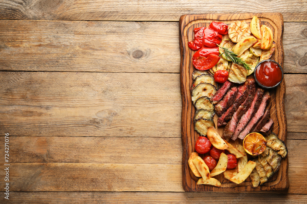Delicious grilled beef with vegetables, rosemary and tomato sauce on wooden table, top view. Space for text Delicious grilled beef with vegetables, rosemary and tomato sauce on wooden table, top view. Space for text