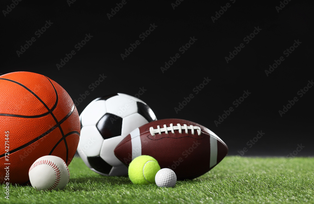 Many different sports balls on green grass against black background, space for text Many different sports balls on green grass against black background, space for text