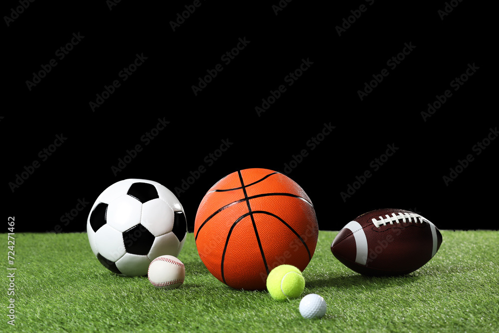 Many different sports balls on green grass against black background, space for text Many different sports balls on green grass against black background, space for text
