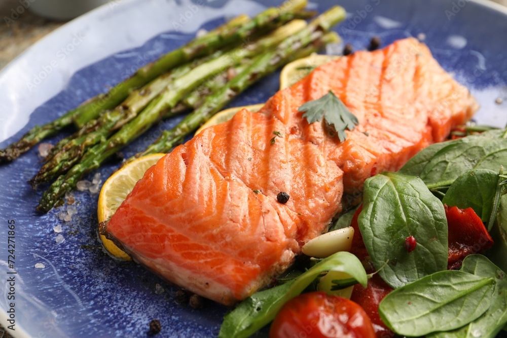 Tasty grilled salmon with tomatoes, asparagus, spinach and spices on plate, closeup Tasty grilled salmon with tomatoes, asparagus, spinach and spices on plate, closeup