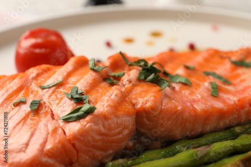 Tasty grilled salmon with tomato and spices on plate, closeup
