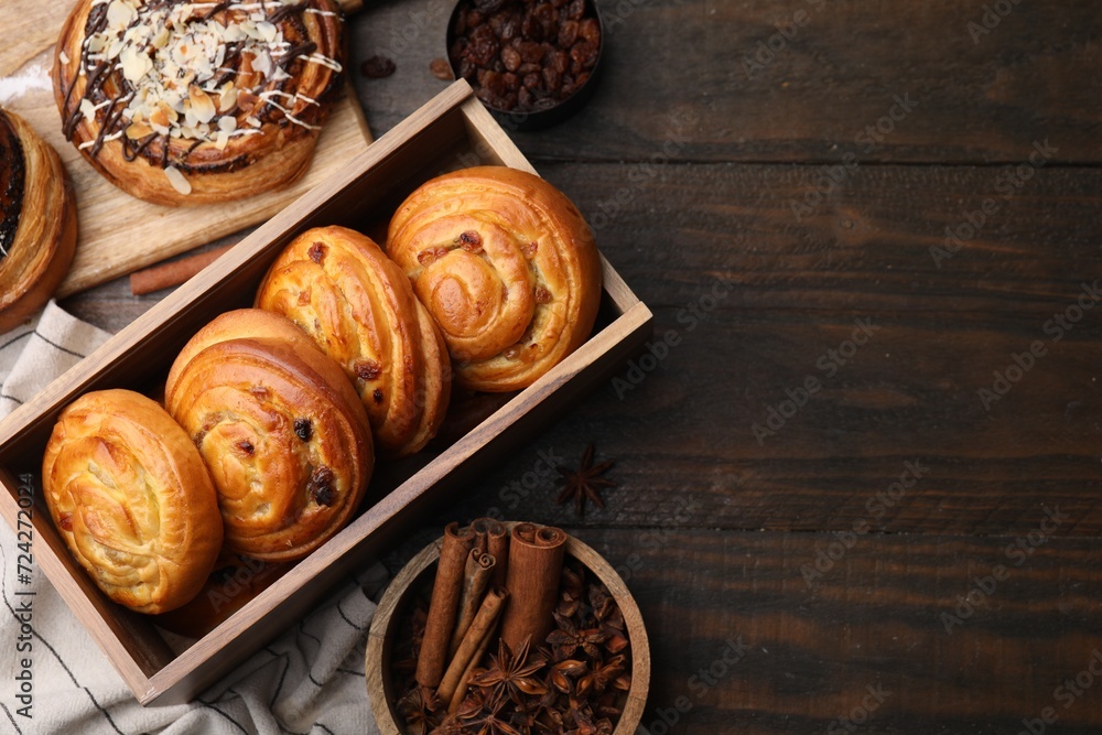 Different delicious rolls and spices on wooden table, flat lay and space for text. Sweet buns Different delicious rolls and spices on wooden table, flat lay and space for text. Sweet buns