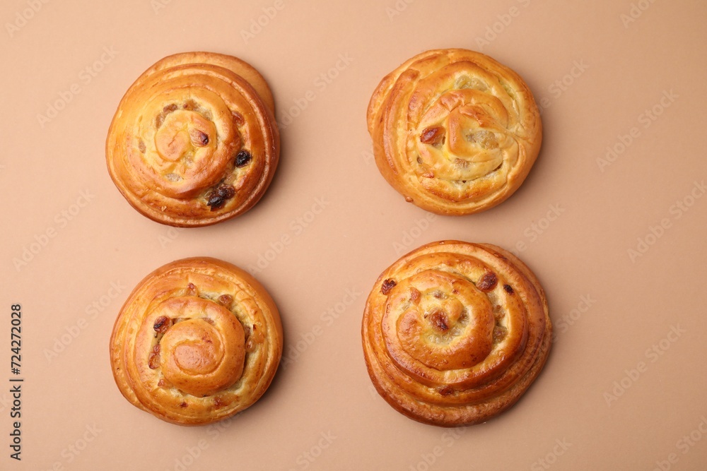 Fototapeta premium Delicious rolls with raisins on beige table, flat lay. Sweet buns