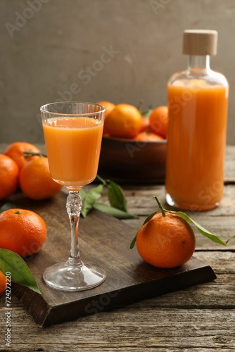 Delicious tangerine liqueur and fresh fruits on wooden table