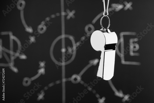 Referee whistle against chalkboard with game scheme, closeup. Space for text