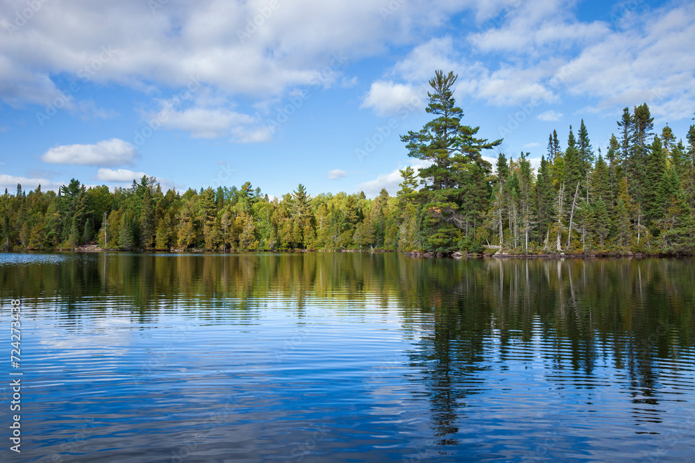 Blue lake in northern Minnesota with pines along the shore during autumn