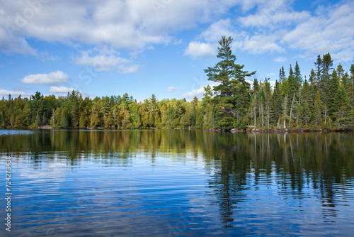 Blue lake in northern Minnesota with pines along the shore during autumn