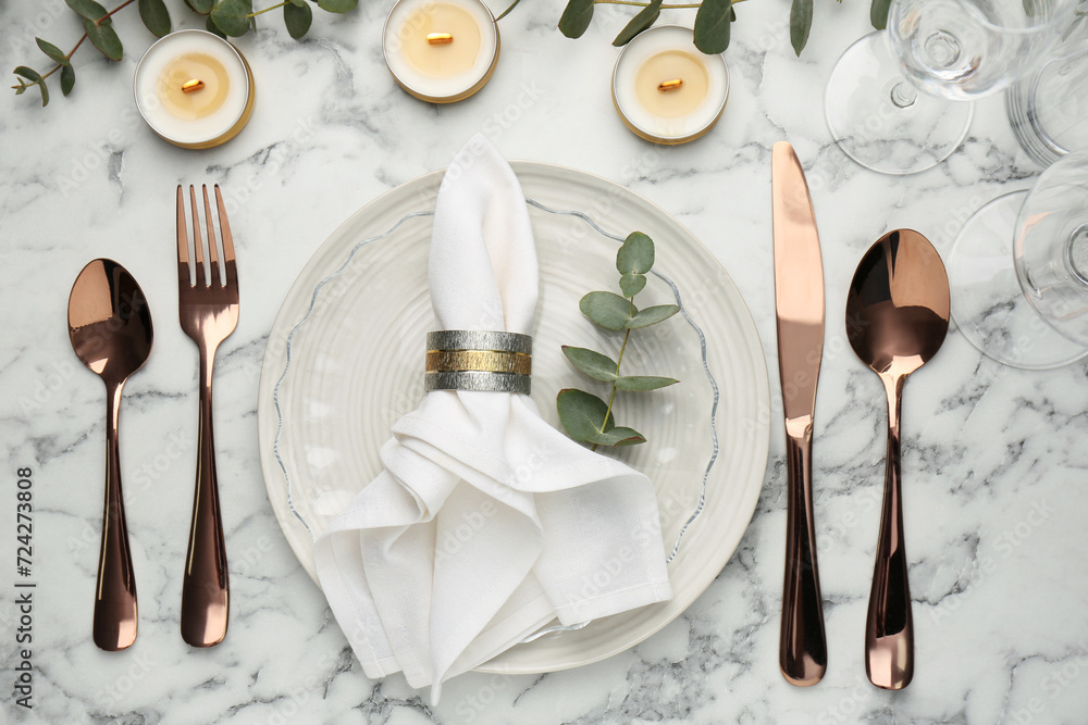 Beautiful place setting with candles and eucalyptus on white marble table, flat lay