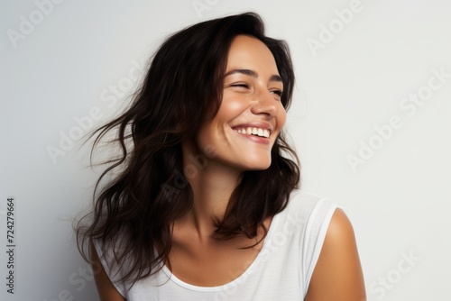 Portrait of beautiful young woman smiling and looking at camera on grey background
