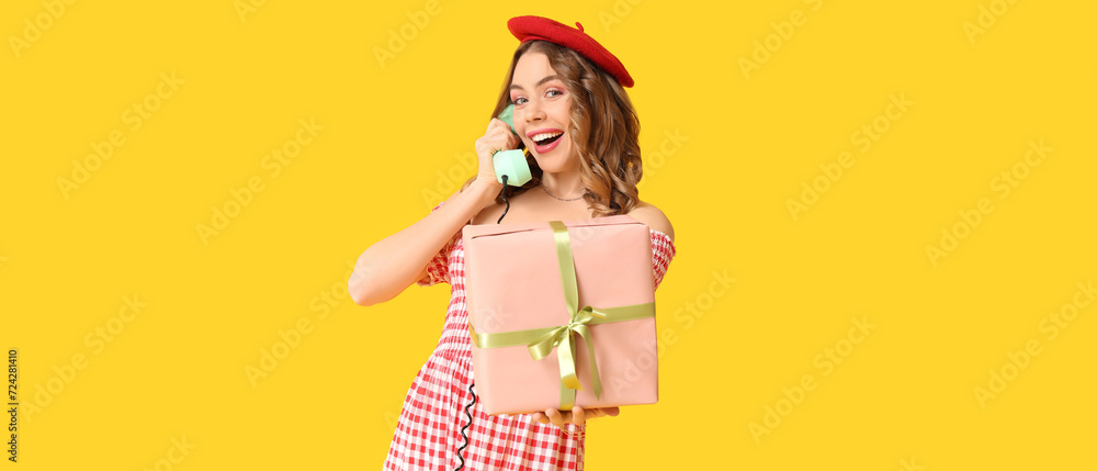 Young woman with gift talking by retro telephone on yellow background. International Women's Day Young woman with gift talking by retro telephone on yellow background. International Women's Day