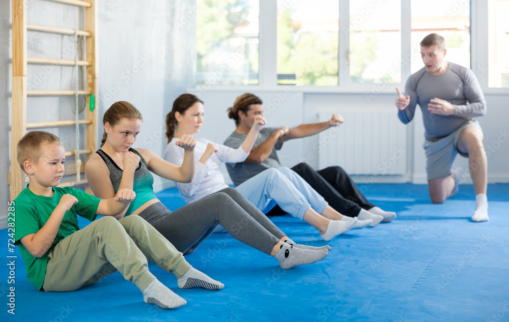 Obraz premium Family in gym perform abdominal training techniques while simultaneously performing punches