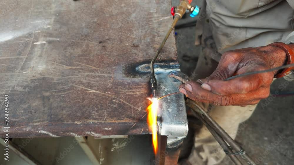 closeup of Welders hand doing gas weld with sparks flying as metal is being on a workbench at workshop closeup of Welders hand doing gas weld with sparks flying as metal is being on a workbench at workshop
